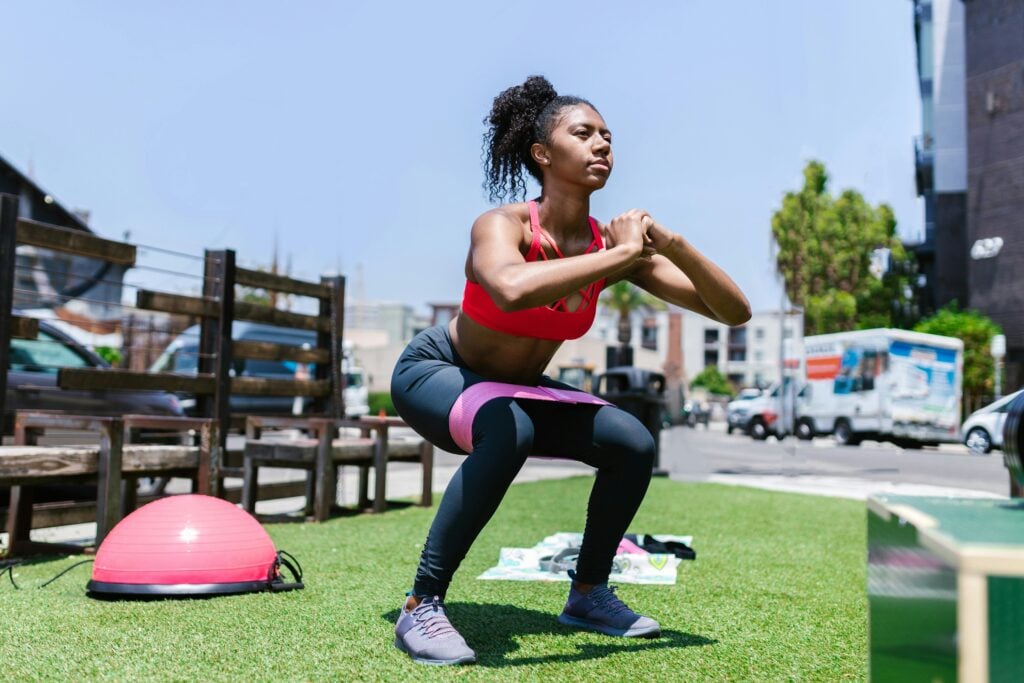 Frau macht Squats auf Outdoor Fitnessanlage