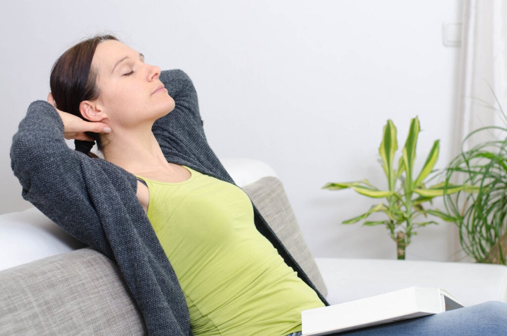 Frau auf Sofa massiert ihren Nacken