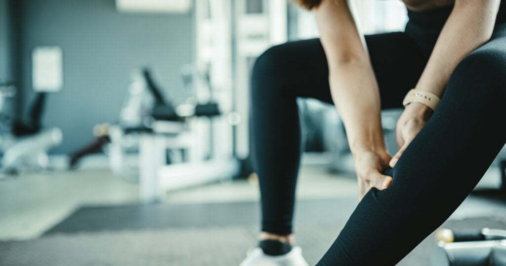 Frau hält sich schmerzendes Bein mit Muskelkater