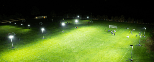Sportplatz Flutlicht online kaufen im Kübler Sport Onlineshop Flutlichtanlage auf einem beleuchteten Fußballplatz bei Nacht mit klar sichtbaren Flutlichtmasten und Spielfeld