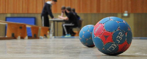 Mehrere Handball Trainingsbälle verschiedener Größen und Farben für Schule, Verein und Training auf einem Spielfeld