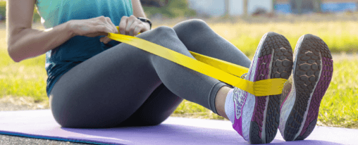 Frau trainiert mit Gymnastikband bei Fitnessübungen im Studio