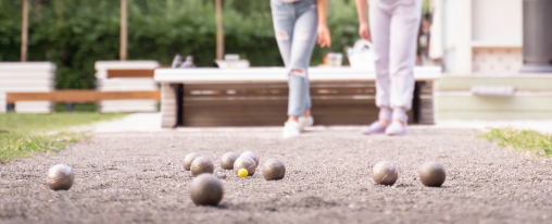 Boule Kugeln online kaufen im Kübler Sport Onlineshop Mehrere Boule Kugeln mit Zielkugel auf einem sandigen Spielfeld als Freizeitspiel