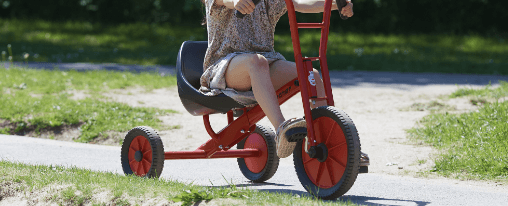 Dreirad online kaufen: Freizeitspiele im Kübler Sport Onlineshop Mehrere Kinder fahren Dreirad im Freien auf einem Spielplatz
