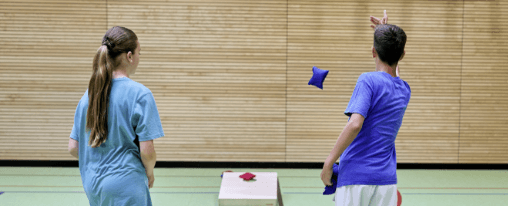 Personen spielen Cornhole im Freien mit Säckchen und Holzbrettern – beliebtes Wurfspiel für Freizeit, Familie und Freunde
