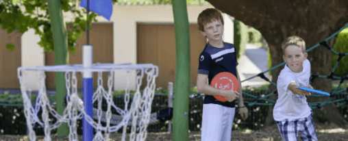 Zwei Kinder spielen auf dem Schulhof das Wurfspiel Disc Golf