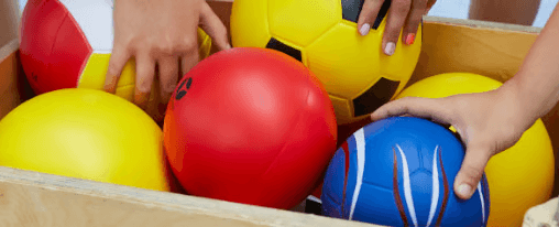 Verschiedene bunte Softbälle in einem umgedrehten Sprungkasten
