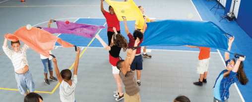 Zirkusartikel online kaufen: Freizeitspiele im Kübler Sport Onlineshop Kinder in einer Sporthalle mit verschiedene farbenfrohe Zirkusartikel als Freizeitspiele