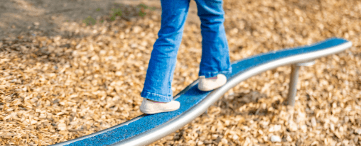 Kinder balancieren auf einem Balancierbalken auf einem Spielplatzger&auml;t