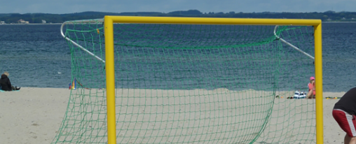 Teamsportler bauen ein Beach Soccer Tor auf Sand f&uuml;r ein Fu&szlig;ballspiel am Strand auf