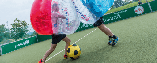 Teamsport-Gruppe spielt Bubble Soccer mit Bubble Balls in einer Sportarena