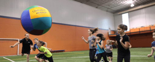 Teamsportgruppen spielen mit einem Kin-Ball in der Halle – jetzt Kin-Ball kaufen bei Kübler Sport