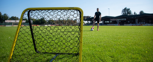 Rebounder Fußball online kaufen im Kübler Sport Onlineshop Mehrere Rebounder Fußball für Fußballtraining im Vereinsbedarf auf einem Sportplatz mit Spielern