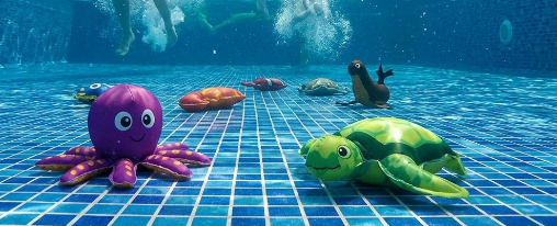 Verschiedene bunte Tauchtiere f&uuml;r Wassersport und Schwimmtraining liegen am Beckenrand