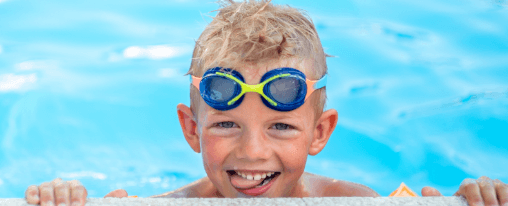 L&auml;chelndes Kind mit Schwimmbrille beim Schwimmen im Hallenbad