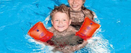 Mehrere bunte Schwimmfl&uuml;gel liegen am Beckenrand eines Schwimmbads