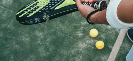 Zwei Padel Tennis Bälle liegen auf dem Boden, Spieler mit Schläger