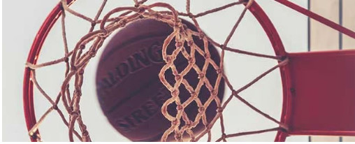 Basketball-Ausrüstung kaufen Basketballkorb mit Basketball perspektivisch von unten fotografiert mit Himmel
