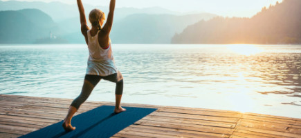 Frau macht am See Übungen auf einer Gymnastikmatte