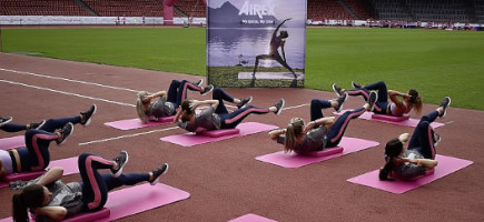 Gruppenfitnesskurs führt Übungen auf AIREX Matten auf einem Sportplatz durch