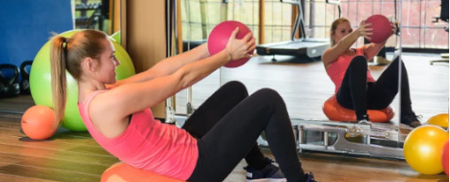 Frau macht Übungen in einem Fitnessstudio mit einem Medizinball