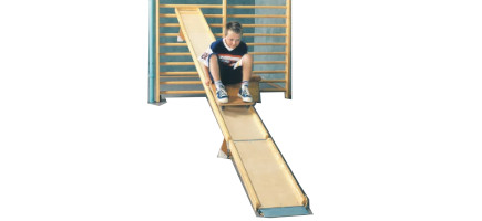 Eine Holz-Rollbrettbahn in einer Sprossenwand befestigt, Kind rutscht darauf herunter