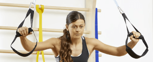 Slingtrainer kaufen Athletin trainiert an einem Slingtrainer als Erweiterung an einer Sprossenwand
