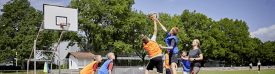 Robuste Outdoor-Basketballanlage auf einem Sportplatz bei Nutzung durch mehrere Spieler