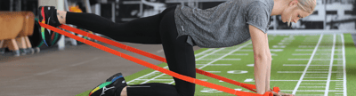 Frau im Fitnessstudio führt Übungen mit einem Pilates Band aus