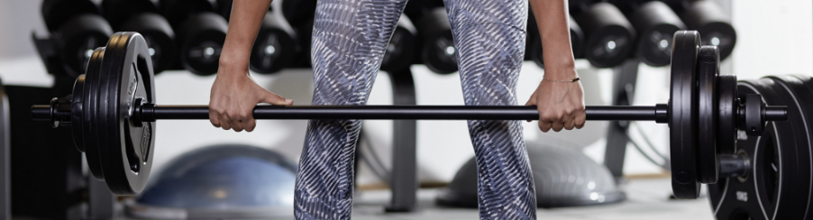 Frau führt eine Kreuzheben-Übung mit einer Langhantelstange aus, um die Rückenmuskulatur und Beine zu stärken.