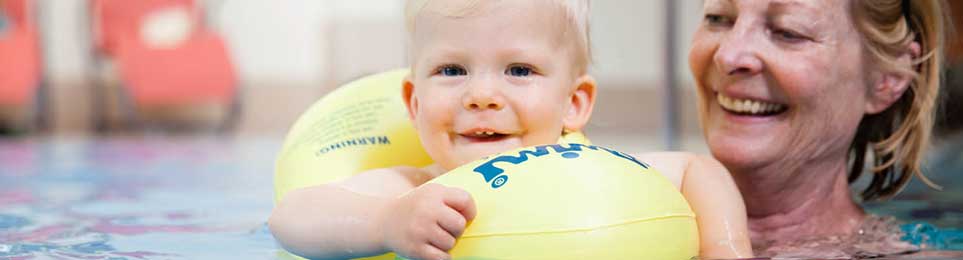 Kinder verschiedener Altersgruppen nutzen Schwimmflügel, Schwimmgürtel und weiteres Schwimmzubehör beim Schwimmen im Wasser