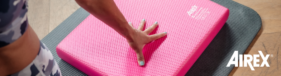 Frau mit einer grauen Airex Matte und einem pinken Airex Balance Pad