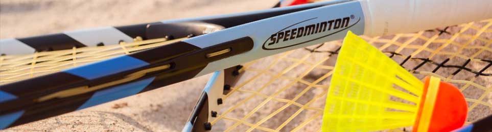 Personen spielen Crossminton auf einem markierten Spielfeld mit Schlägern und Speeder-Bällen