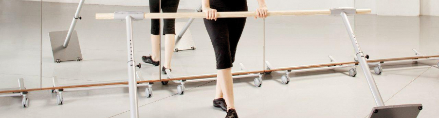 Ballett-Tänzering verschiebt eine freistehende Ballettstange im Tanzraum