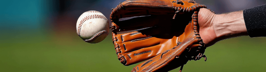 Teamsport-Spieler mit Baseballhandschuh beim Fangen eines Baseballs auf dem Spielfeld