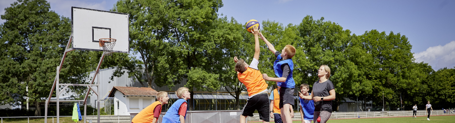 Robuste Outdoor-Basketballanlage auf einem Sportplatz bei Nutzung durch mehrere Spieler