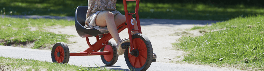 Kind fährt Dreirad im Freien auf einem Spielplatz