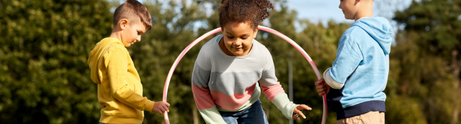 Kinder spielen mit Hula Hoop Reifen bei einem Freizeitspiel im Freien