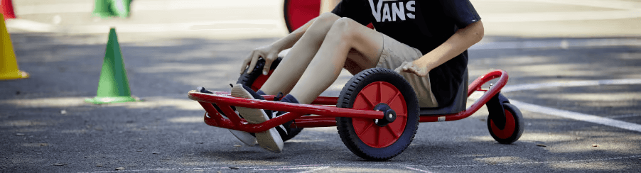 Verschiedene Kinderfahrzeuge für Freizeitspiele, draußen genutzt von Kindern unterschiedlichen Alters