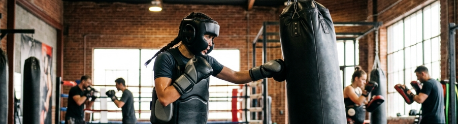 Kampfsportler tragen Schutzausrüstung wie Kopfschutz, Tiefschutz, Brustschutz und Schienbeinschoner beim Training