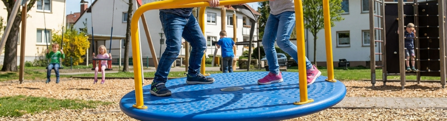 Kinder spielen auf einer Kreiselwippe als robustem Spielplatzgerät im Freien