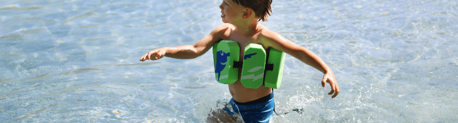 Kind trägt einen Schwimmgürtel im Wasser während des Schwimmunterrichts