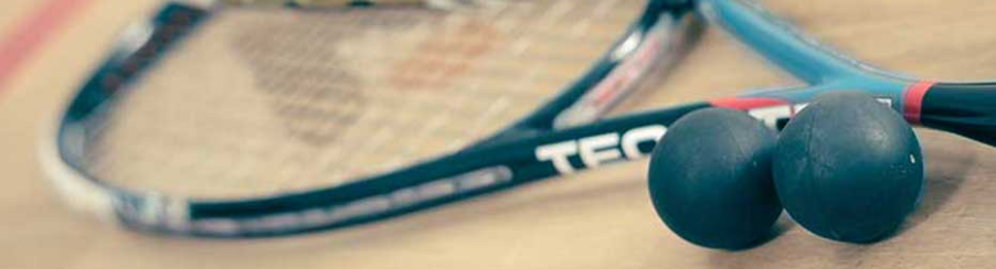 Verschiedene Squashbälle für Training und Wettkampf, passend für unterschiedliche Spielniveaus, auf einem Spielfeld platziert