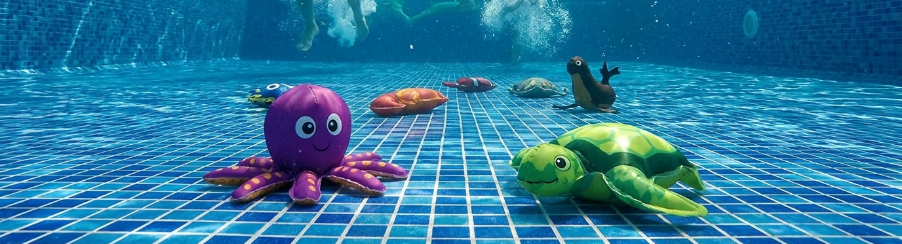 Verschiedene bunte Tauchtiere für Wassersport und Schwimmtraining liegen am Beckenrand