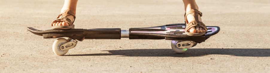Kinder und Jugendliche beim Streetsurfing mit einem Waveboard für Freizeitspiele auf dem Asphalt