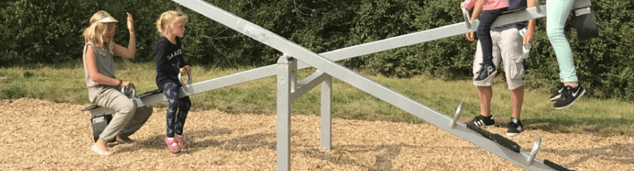 Kinder spielen auf verschiedenen Wippgeräten auf einem modernen, öffentlichen Spielplatz