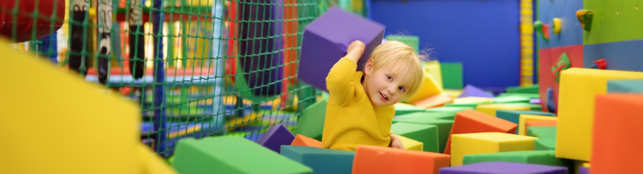 Kind in Bewegungslandschaft mit vielen bunten Schaumstofblöcken